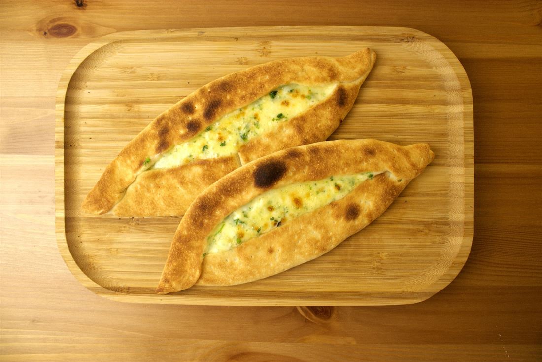 Two cheese boat pies with parsley on a wooden board